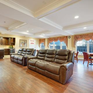 A spacious living room with comfortable leather sofas, hardwood flooring, and a dining area in the background.