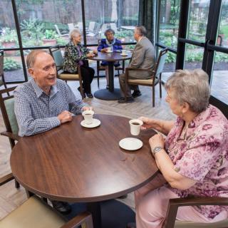 Elderly couples enjoying coffee and conversation in a cozy cafe setting.
