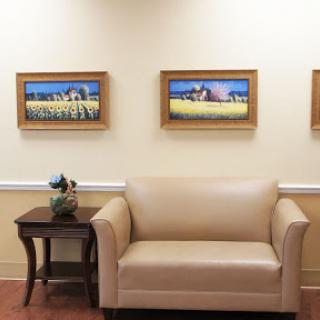 A cozy waiting area featuring a beige sofa, decorative wall art, and a small table with a plant.