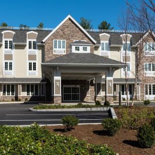 A modern residential building with a landscaped entrance and stone accents.