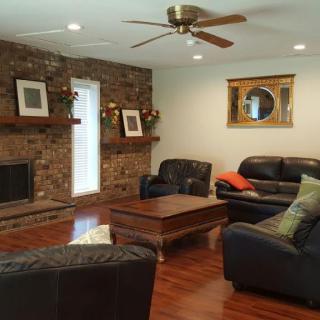 A cozy living room with a stone fireplace, leather couches, and wooden floors.