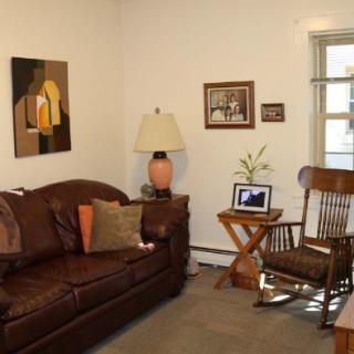 A cozy living room with a leather sofa, rocking chair, and decorative elements.