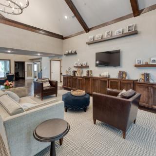 A spacious living room with cozy seating and a modern television, featuring wood accents and decorative shelving.