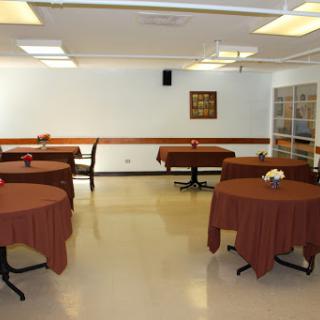 A spacious dining area with round tables covered in brown tablecloths, set in a well-lit room.