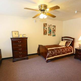 A cozy bedroom featuring a single bed, dresser, and ceiling fan.