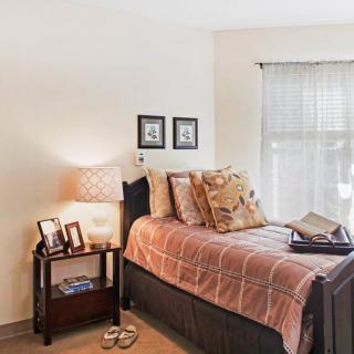 A cozy bedroom with a single bed, decorative pillows, and a side table with a lamp.