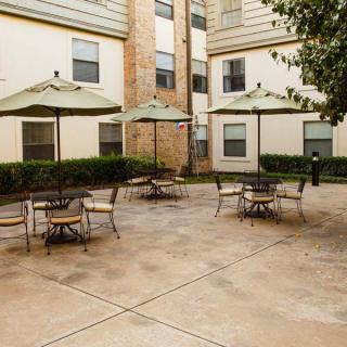 An outdoor patio area with tables, chairs, and umbrellas in an apartment complex.