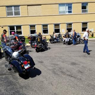 Bikers gathered in a parking lot, enjoying the sunny weather and camaraderie.