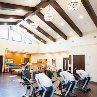 A spacious gym area featuring modern exercise equipment and a stylish interior design with wooden beams.