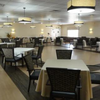 An empty dining room with neatly arranged tables and chairs, featuring ambient lighting.