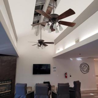 A modern living room interior featuring ceiling fans, a television, and comfortable seating.