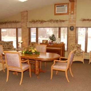 A cozy living room with a round dining table and chairs by large windows.