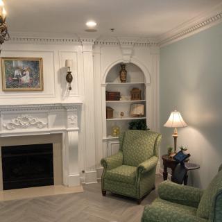 A cozy living room with a fireplace and green armchairs.