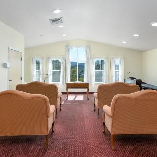 A well-lit room with chairs arranged facing a set of windows.