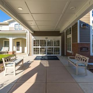 A covered outdoor entrance with benches leading to a building under a sunny sky.