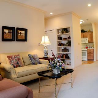 Cozy living room with a view into the kitchen, featuring a comfortable sofa, decorative pillows, and elegant lighting.