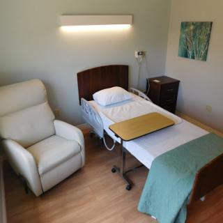 A cozy hospital patient room featuring a bed, a recliner chair, and soft lighting.
