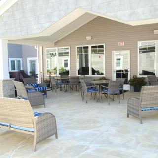 A spacious outdoor patio with wicker furniture and tables under a covered area.