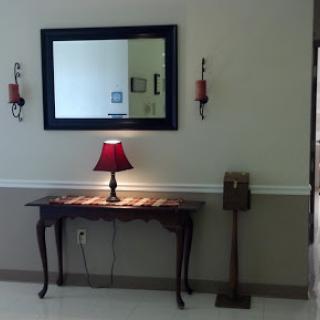 A stylish interior scene featuring a mirror above a decorated table with a lamp and wall sconces.