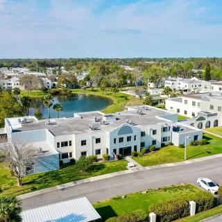 A scenic aerial view of a suburban residential area with houses, a lake, and lush greenery.