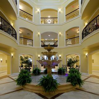 A spacious indoor atrium with balconies, featuring a central fountain surrounded by greenery.
