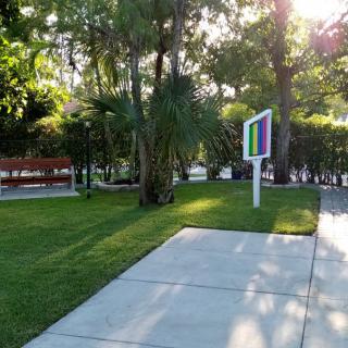 A serene park setting with a pathway, benches, and lush greenery.