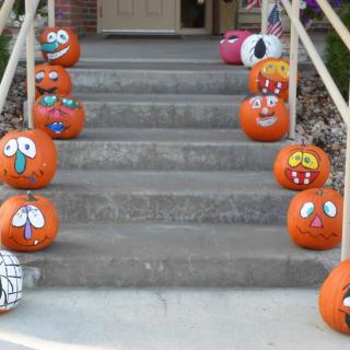 A collection of creatively decorated pumpkins with various expressive faces lined up on the stairs.