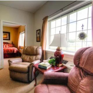 A cozy living room with armchairs by a sunlit window.