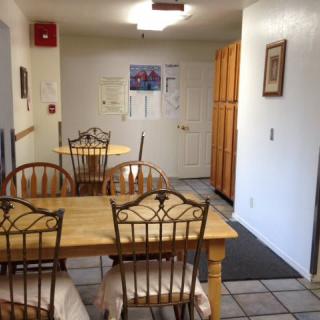 A cozy dining area with wooden tables and chairs, featuring wall decorations in a home-like setting.