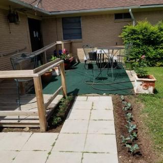 A backyard patio with a ramp, outdoor furniture, and a small garden area.