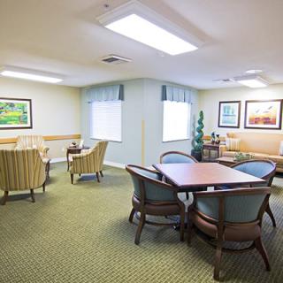 A cozy seating area with tables, chairs, and artwork on the walls.