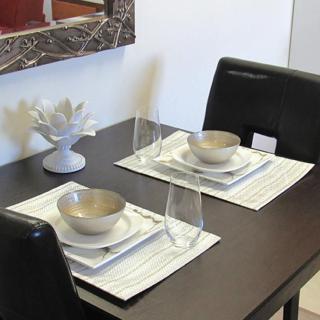 A modern dining table set for two with minimalist dinnerware and glassware.