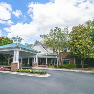 A well-maintained building entrance surrounded by trees under a partly cloudy sky.