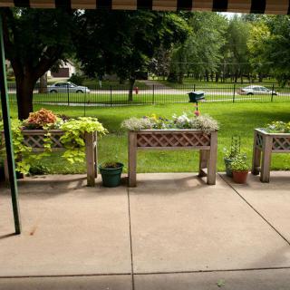A patio with planters overlooking a green lawn and trees.