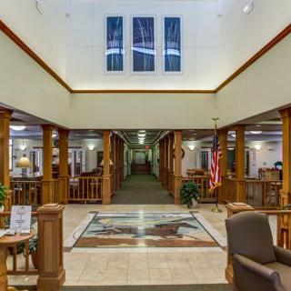 A spacious lobby with wooden columns and a decorative rug leading to a hallway.