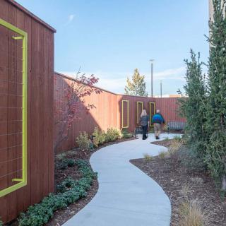 A modern outdoor garden with a winding pathway between architectural wooden structures.