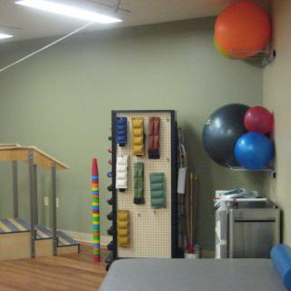 A rehabilitation room equipped with exercise balls and various therapy tools.