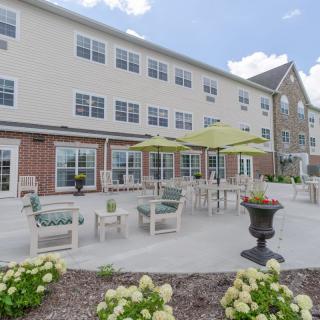 A well-maintained patio area with outdoor seating and umbrellas in front of a residential building.