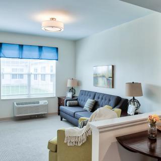 A cozy living room with a blue sofa, bright window treatments, and elegant decor.