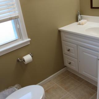 A small bathroom with a white vanity and tiled floor.