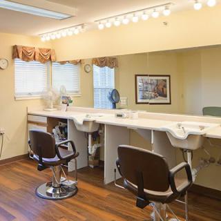 A bright barber shop interior with chairs, mirrors, and sinks lined up along the counter.
