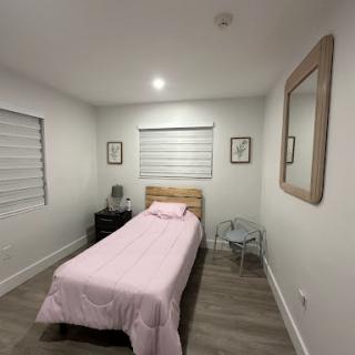 A cozy and minimalist bedroom featuring a single bed with pink bedding and modern decor.