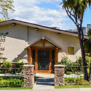 A well-maintained house with a wooden entrance surrounded by lush greenery and trees.