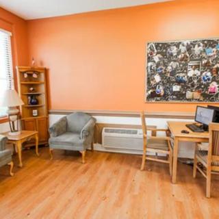 A cozy room with orange walls, featuring a comfortable seating area and a computer desk.