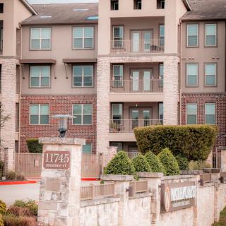 A multi-story apartment building with balconies and well-maintained landscaping.