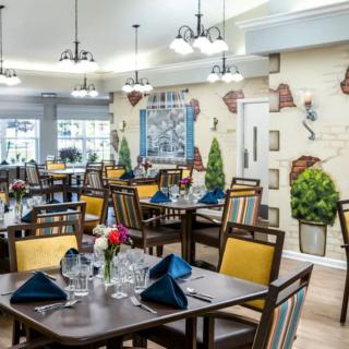 A well-decorated dining room featuring arranged tables with colorful napkins and elegant lighting.