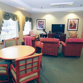 A cozy living room with comfortable seating, a television, and a round table by the window.