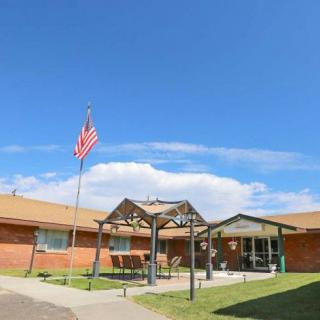 A brick building with an entrance canopy and an American flag waving on a clear day.