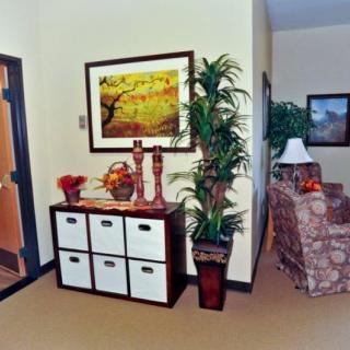 A cozy living room corner with a decorative sideboard, framed artwork, and indoor plants.