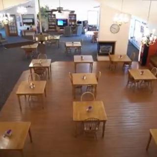 An empty restaurant dining area with neatly arranged tables on a wooden floor.